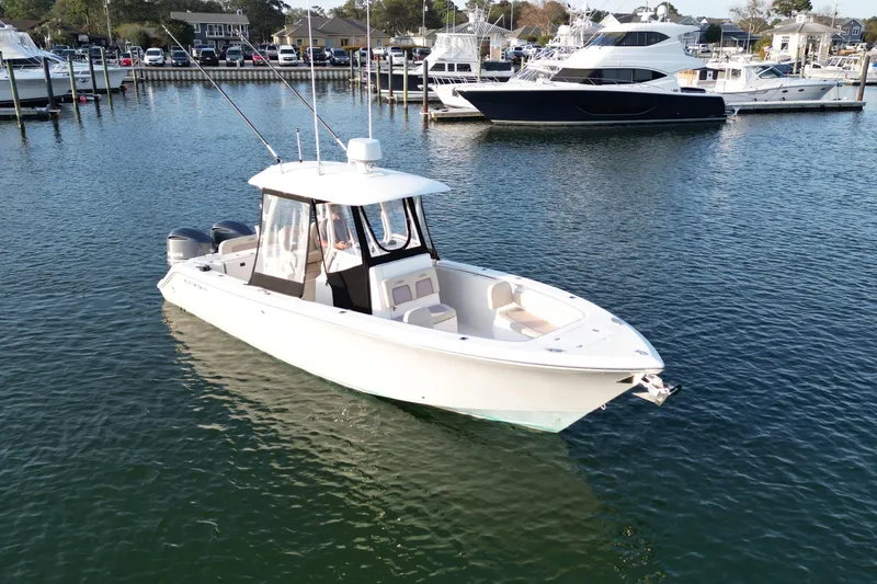 Slide: The Image of 2016 Cobia 296 Center Console boat docked in a marina, surrounded by other vessels. - 5