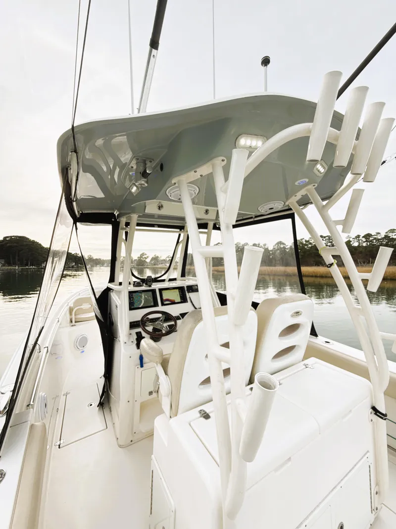 Slide: The Image of 2016 Cobia 296 Center Console boat with helm and seating, docked on calm water. - 16