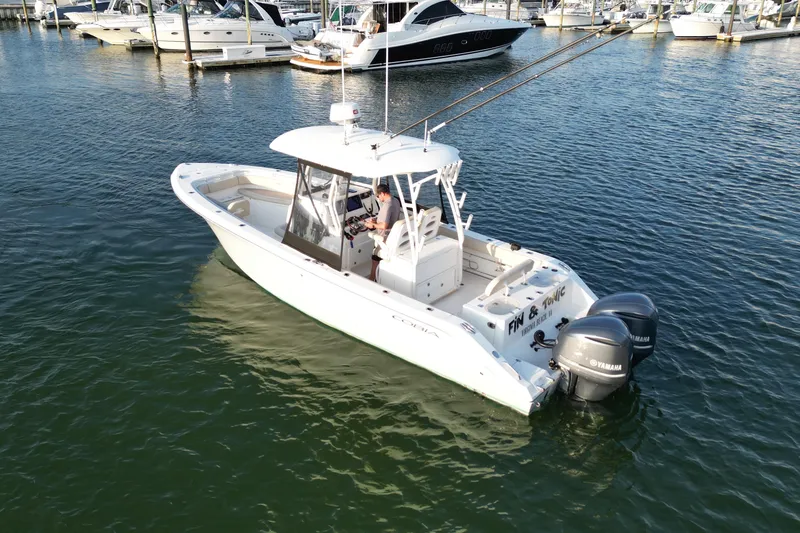 Slide: The Image of 2016 Cobia 296 Center Console boat with dual Yamaha engines in a marina setting. - 4
