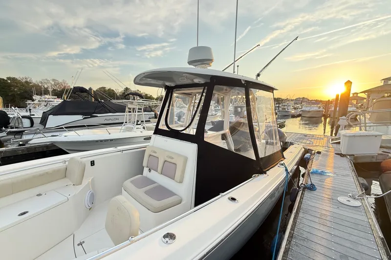 Slide: The Image of 2016 Cobia 296 Center Console boat docked at sunset, featuring sleek design and spacious seating. - 23
