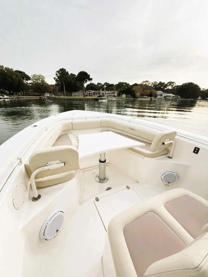 Slide: The Image of 2016 Cobia 296 Center Console boat interior with seating and table on calm water. - 9