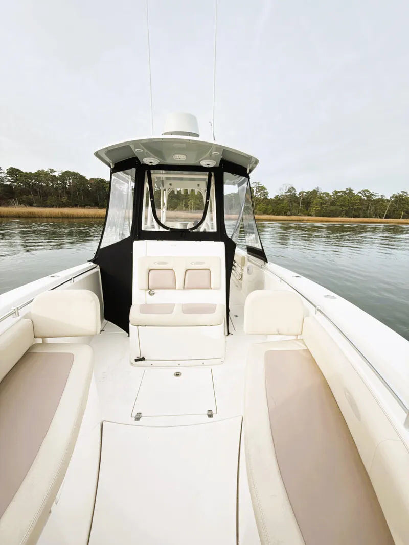Slide: The Image of 2016 Cobia 296 Center Console boat on calm water, featuring spacious seating and sleek design. - 12