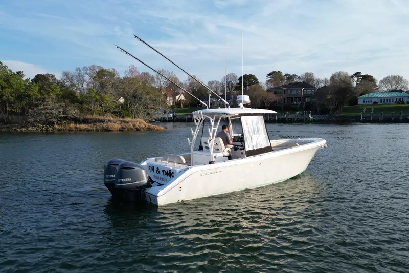 Slide: The Image of 2016 Cobia 296 Center Console boat on calm water with fishing rods. - 2