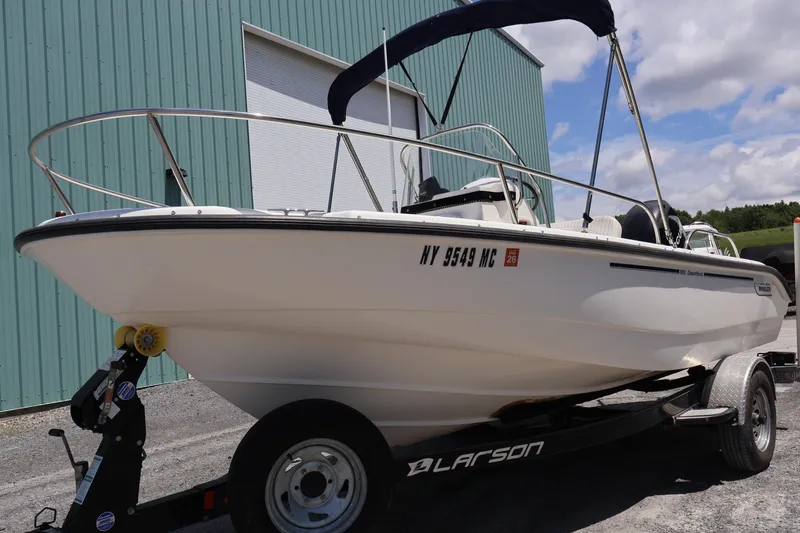 The Image of 2007 Boston Whaler 180 Dauntless boat on trailer, parked near a green building. - 0