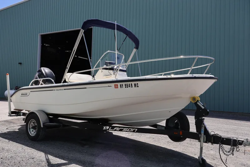 Slide: The Image of 2007 Boston Whaler 180 Dauntless boat on trailer, parked outside a large building. - 3
