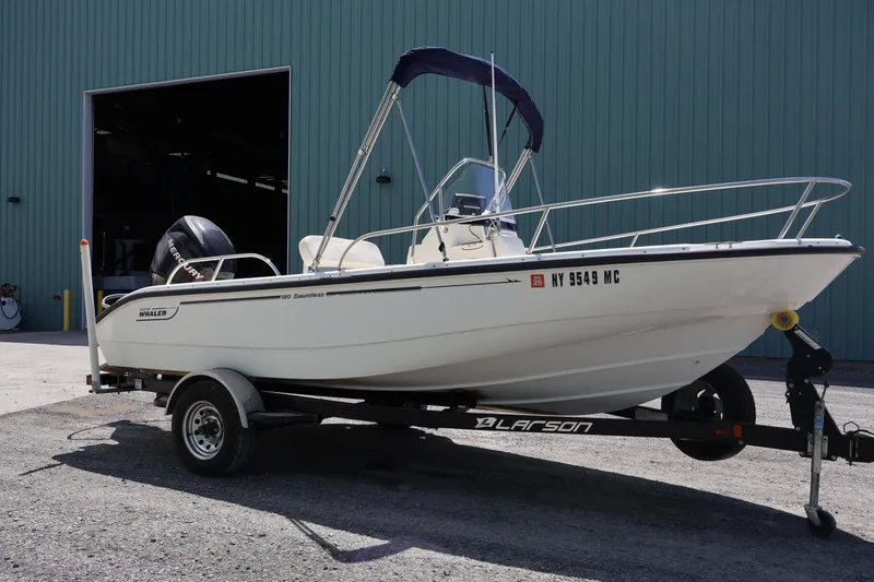 Slide: The Image of 2007 Boston Whaler 180 Dauntless boat on trailer, parked outside a large building. - 1