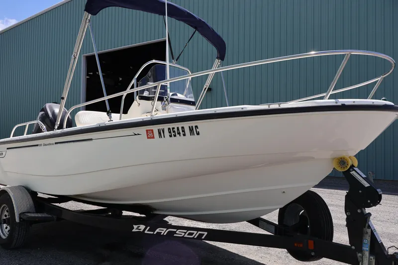 Slide: The Image of 2007 Boston Whaler 180 Dauntless boat on trailer, parked outside a blue building. - 2