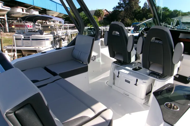 Slide: The Image of 2026 Monterey Elite 25 SD boat interior with seating and helm, docked near other boats. - 3