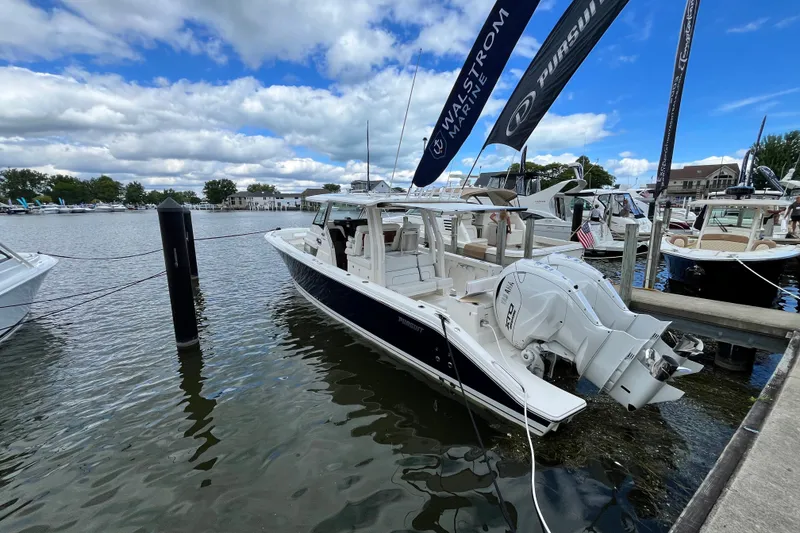 Slide: The Image of 2027 Pursuit S 358 Sport boat docked at marina under blue sky. - 2