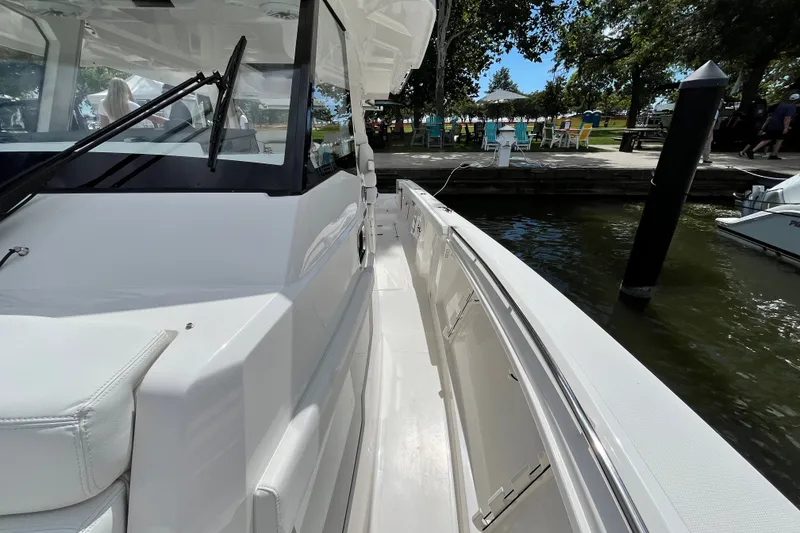 Slide: The Image of 2027 Pursuit S 358 Sport boat docked by a scenic waterfront. - 8