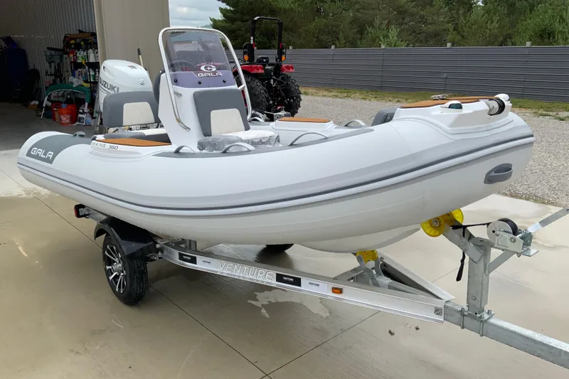 Slide: The Image of Gala V360 inflatable boat on trailer, featuring Suzuki engine, parked outdoors. - 4