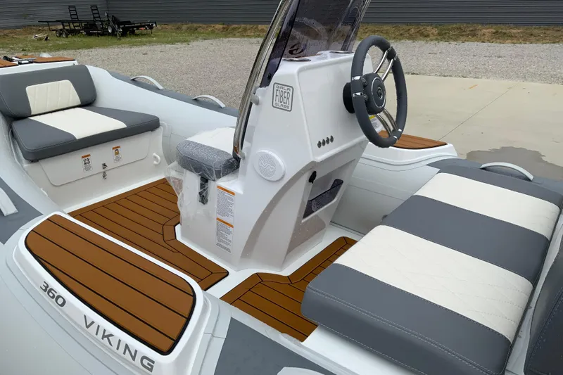 The Image of 2027 Gala V360 boat interior with steering wheel, cushioned seats, and wood-style flooring. - 1