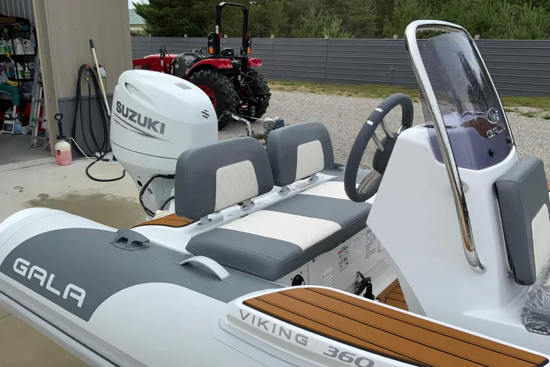 Slide: The Image of Inflatable boat Gala V360 (2027) with Suzuki outboard motor, parked near a garage. - 6