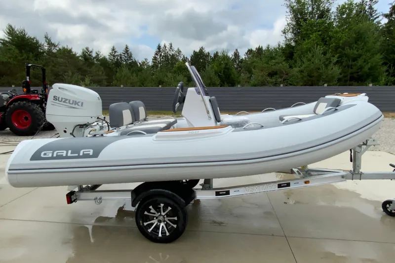 Slide: The Image of 2027 Gala V360 inflatable boat with Suzuki engine on a trailer, parked outdoors. - 7
