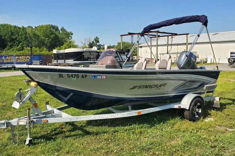 Slide: The Image of 2022 Starcraft Stealth 166 SC boat on trailer, parked on grass near industrial buildings. - 0