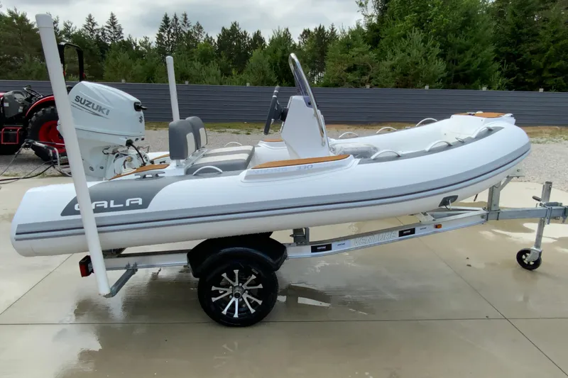 Slide: The Image of 2027 Gala V330 inflatable boat on trailer with Suzuki outboard motor, parked outdoors. - 4