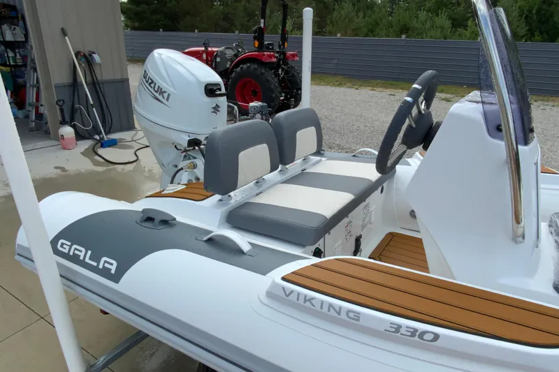 Slide: The Image of 2027 Gala V330 inflatable boat with Suzuki outboard motor, parked near a garage. - 3