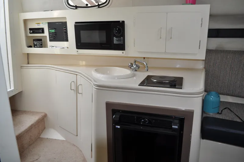 Slide: The Image of 1997 Carver 260 Mid Cabin Express interior with kitchenette, microwave, sink, and compact appliances. - 4