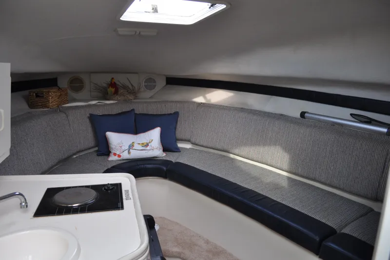 Slide: The Image of 1997 Carver 260 Mid Cabin Express interior with cozy seating and compact kitchenette. - 11