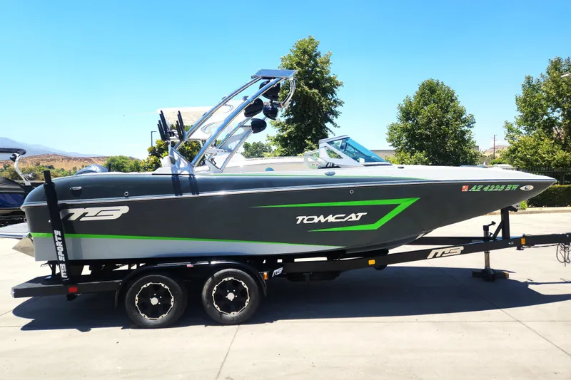 The Image of 2015 MB SPORTS F22 Tomcat boat on trailer, featuring sleek design and vibrant green accents. - 1