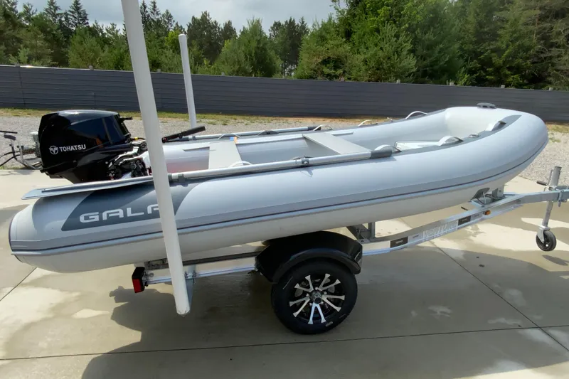 Slide: The Image of Inflatable boat Gala A330D 2027 on trailer with Tohatsu motor, parked outdoors. - 6