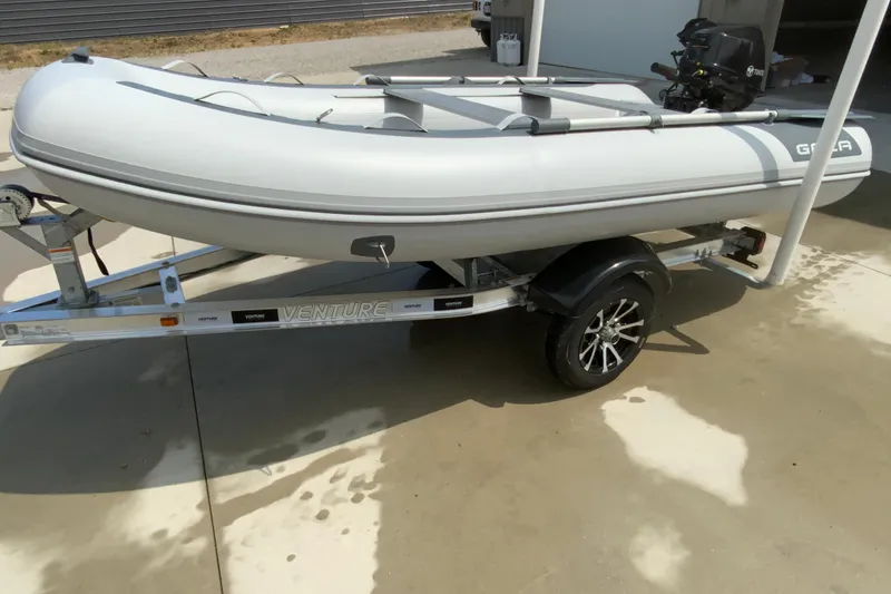 Slide: The Image of 2027 Gala A330D inflatable boat on a Venture trailer, parked on a concrete surface. - 4