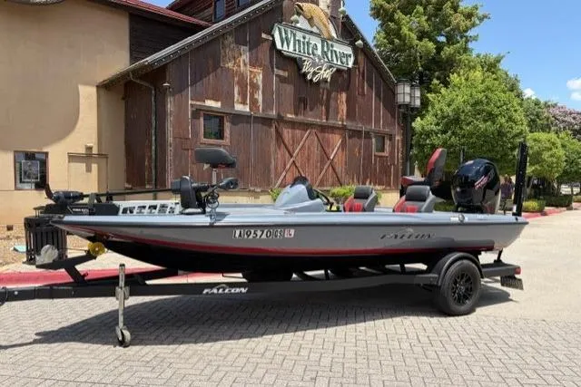 The Image of 2025 Falcon Boats F-18 on trailer, parked outside rustic building with "White River" sign. - 0