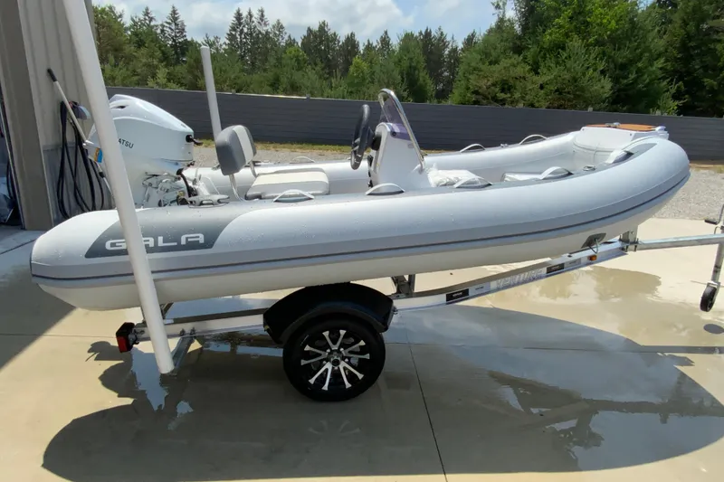 Slide: The Image of 2027 Gala A330L inflatable boat on trailer, parked outdoors, with trees in the background. - 8