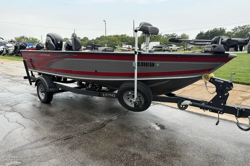 Slide: The Image of 2024 Lund 1875 Pro Guide boat on trailer, parked outdoors on wet pavement. - 1