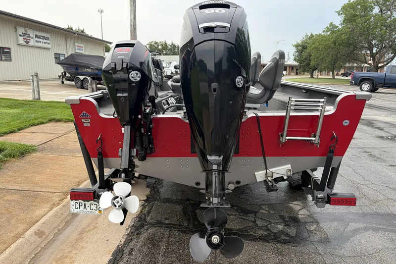 Slide: The Image of 2024 Lund 1875 Pro Guide boat with dual Mercury outboard motors, parked near a dealership. - 2