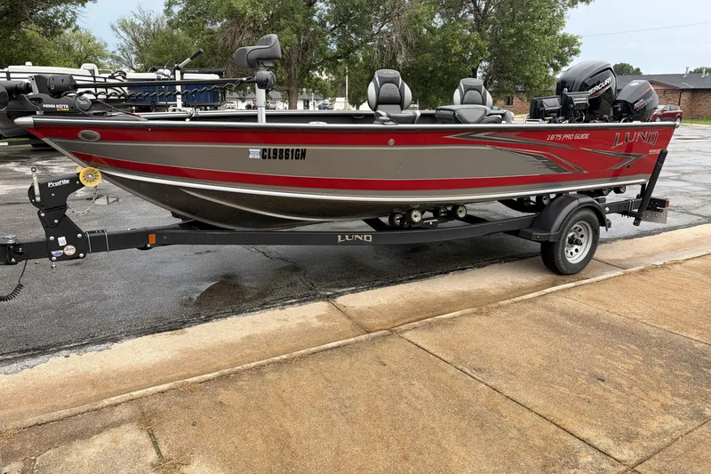 Slide: The Image of 2024 Lund 1875 Pro Guide fishing boat on trailer, parked outdoors. - 3