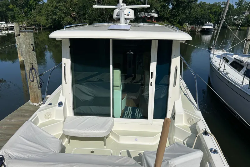 Slide: The Image of 2016 Back Cove 34 boat docked, featuring a spacious deck and sliding glass doors. - 6
