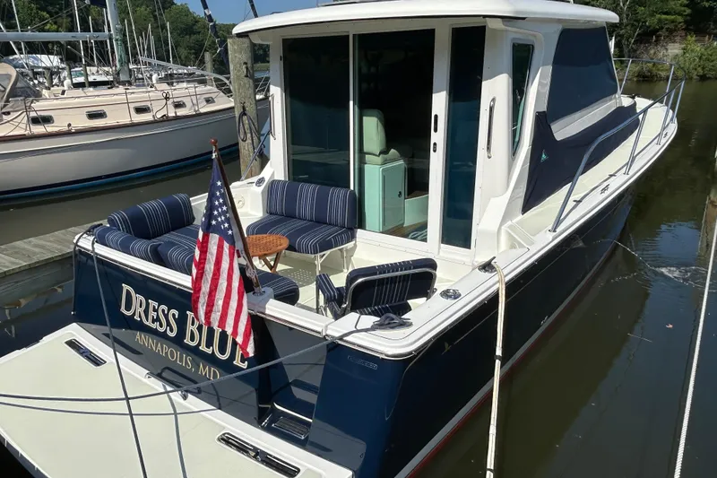 Slide: The Image of 2016 Back Cove 34 boat docked, featuring striped seating and American flag. - 1
