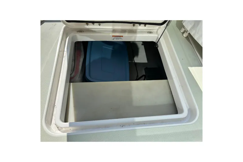 Slide: The Image of Open storage compartment on a 2016 Back Cove 34 boat, featuring a blue container inside. - 19