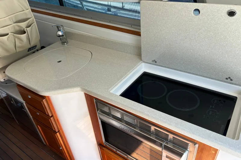 Slide: The Image of 2016 Back Cove 34 yacht kitchen with sink, stove, and wooden cabinetry. - 37