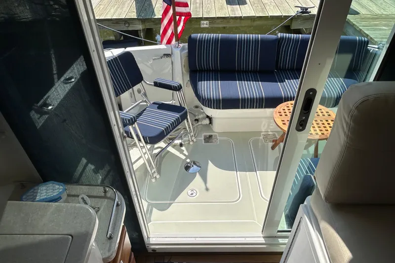 Slide: The Image of 2016 Back Cove 34 boat interior with striped seating and wooden table. - 16