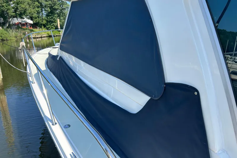Slide: The Image of 2016 Back Cove 34 boat with blue cover docked on calm water. - 5