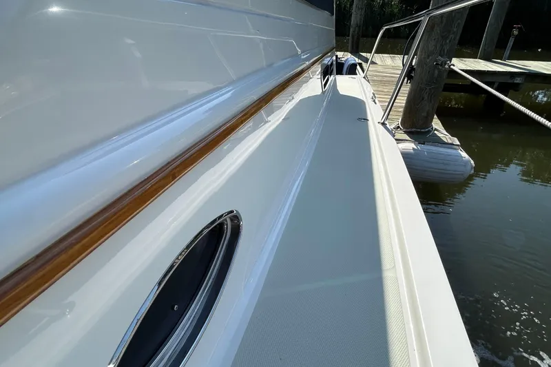 Slide: The Image of 2016 Back Cove 34 yacht docked, showcasing sleek side deck and polished wood trim. - 10