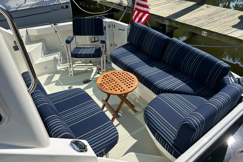 Slide: The Image of 2016 Back Cove 34 boat interior with striped seating and wooden table. - 17