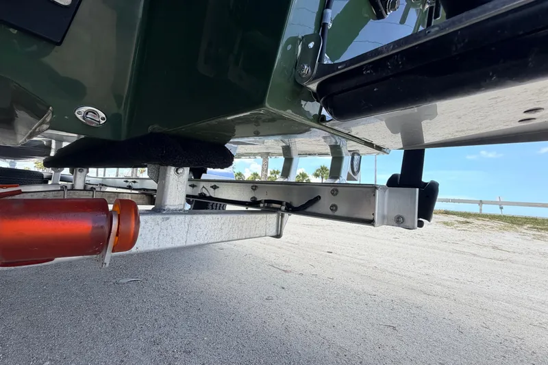 Slide: The Image of Underneath view of a 2025 Hell's Bay Professional boat on a trailer at a sandy location. - 21