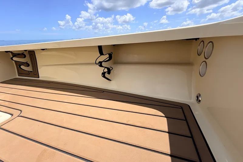 Slide: The Image of 2025 Hell's Bay Professional boat interior with tan deck and rod holders under a blue sky. - 40