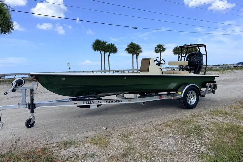 Slide: The Image of 2025 Hell's Bay Professional boat on trailer, parked near palm trees and ocean. - 6