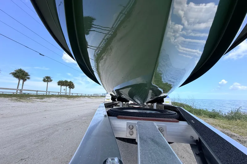 Slide: The Image of 2025 Hell's Bay Professional boat on trailer by the beach, under clear blue sky. - 11