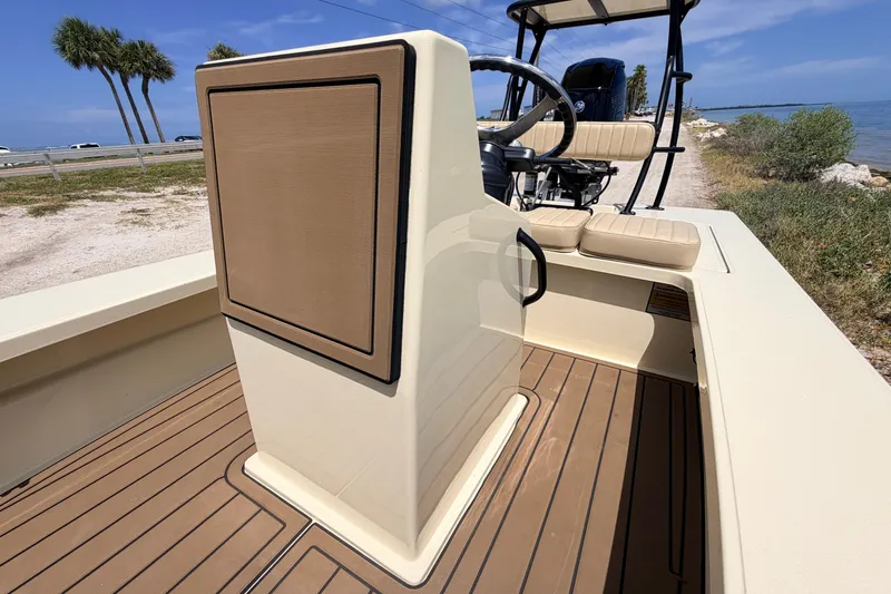 Slide: The Image of 2025 Hell's Bay Professional boat interior with tan seating and steering console, near coastal road. - 42