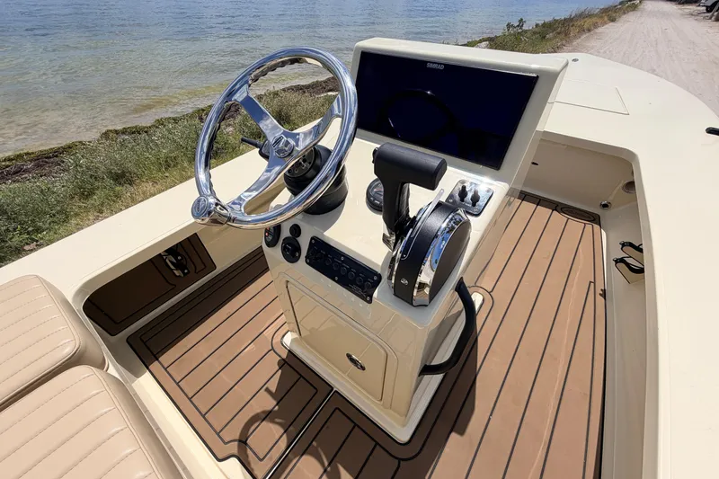 Slide: The Image of 2025 Hell's Bay Professional boat console with steering wheel and controls by the water. - 45