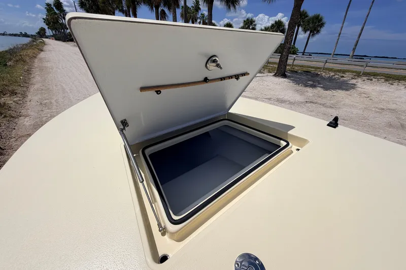 Slide: The Image of 2025 Hell's Bay Professional boat hatch open, revealing storage compartment, with scenic coastal background. - 33
