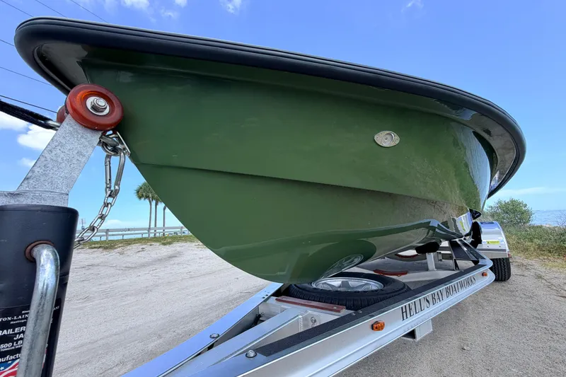 Slide: The Image of 2025 Hell's Bay Professional boat on trailer, green hull, beach background. - 10