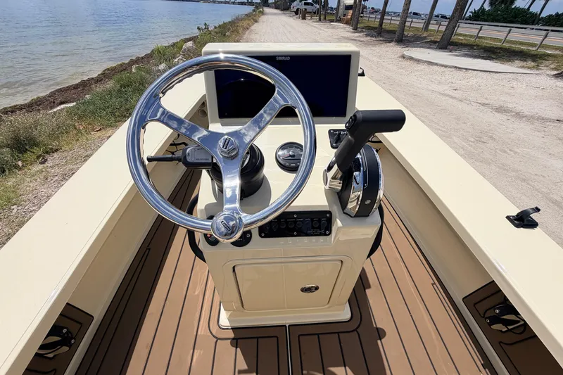 Slide: The Image of 2025 Hell's Bay Professional boat console with steering wheel and controls by the water. - 43