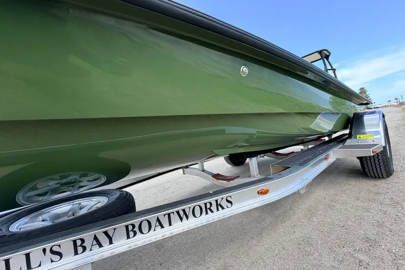 Slide: The Image of 2025 Hell's Bay Professional boat on trailer, showcasing sleek green hull design. - 13