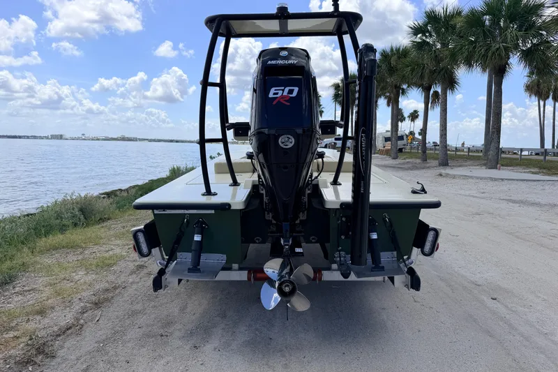 Slide: The Image of 2025 Hell's Bay Professional boat with Mercury 60R engine, parked near a scenic waterfront. - 8
